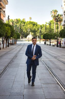 Genç, yakışıklı, koyu renk saçlı, takım elbiseli, kravatlı ve siyah dantelli ayakkabılı bir işadamı Seville 'de büyük bir caddede tramvay rayları arasında yürüyor. Adam çok uluslu bir şirketin yöneticisi.