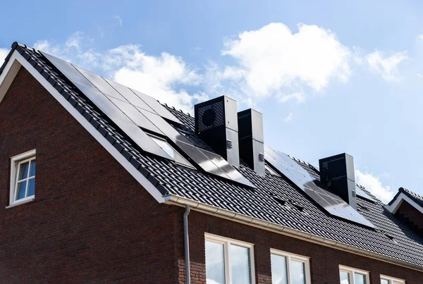 Mavi gökyüzüne karşı yeni binaların kiremitli çatılarındaki güneş panelleri