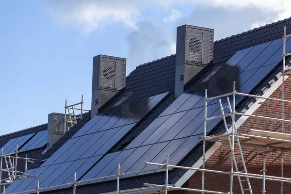 Solar panels on the tiled roofs of new buildings against the blue sky.