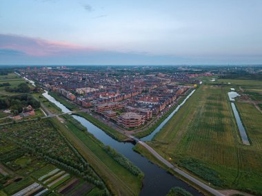 Vathorst 'un Amersfoort, Hollanda' daki su kanalları, tarım alanları ve alacakaranlıkta şehir silueti olan insansız hava aracı görüntüsü..