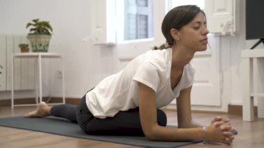 Oturma odasında yoga yapan genç bir kız..