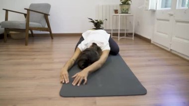 Oturma odasında yoga yapan genç bir kız..