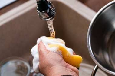 Orta yaşlı bir kadının resmi bulaşıkları yıkıyor..