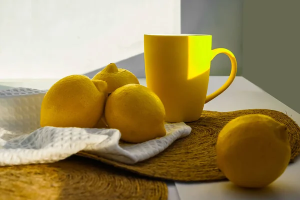 Parlak sarı limonlar ve pencere eşiğinde doğal ışıkta duran bir kupa. Gün, güneş ve gölge. Meyveler, peçeteler, fincanlar, zombisiz arka planda paraşüt altlıkları. Bahar, yaz, ılık.