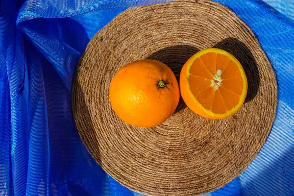 Mavi arka planda yarım portakal var. Yuvarlak jüt standı. Lezzetli ve yeni bir günün vitamini. Turunçgiller çok sağlıklıdır..