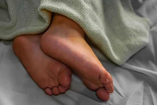 Detailní Záběr Nohy Dítě Spí Posteli Bílém Prostěradle Pokryto Lehkou — Stock fotografie