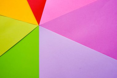Parlak renkli ofis kağıtları beyaz arka planda yukarıdan yakın plan çekilir. Kırmızı, pembe, mor, sarı, turuncu, yeşil