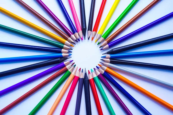 Birçok renkli kalem seti fotoğrafın merkezinde bir daire şeklinde dizilmiştir. Beyaz bir arkaplanda, gün ışığında yukarıdan yakın çekim.