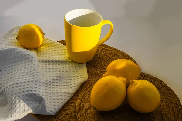 Parlak sarı limonlar ve pencere eşiğinde doğal ışıkta duran bir kupa. Gün, güneş ve gölge. Meyveler, peçeteler, fincanlar, zombisiz arka planda paraşüt altlıkları. Bahar, yaz, ılık.