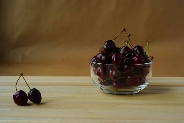 Yanında kiraz kokulu taze kiraz ve iki kiraz içeren bir kase doğal ahşap lamba levhalarının üzerinde yatar. Sulu böğürtlen ve meyveler sağlık ve diyet için vitamin ve şeker kaynağıdır. Sağlıklı beslenme.