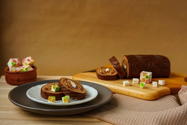 Restoranların ve kafelerin menüsü için fotoğraf. Hafif ahşap yüzey, kasede marmelat, tabakta taze hamur işleri, kesme tahtasında tatlı rulo. Basit, doyurucu bir tatlı.