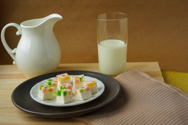 Kırsal kahvaltı - açık ahşap bir masanın üzerinde beyaz bir seramik krema, bir bardak süt ve gri bir tabakta ev yapımı marmelat var. Sağlıklı yemek yeni bir güne harika bir başlangıçtır..