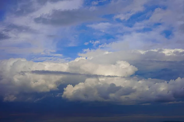 Landscape. Beautiful sky, white aerial cumulus clouds, dark formidable clouds. Weather. Thunderstorm, rain. Background image, texture.