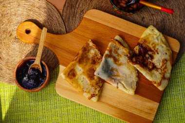 Tahta kesme tahtasına sarılı ev yapımı üçgen krepler. Ve küçük bir kaseye sıkıştır. Tatlı olarak lezzetli yemekler.