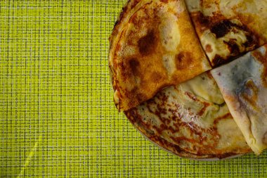 Hasır yeşil peçetelerin arka planında yuvarlak, doyurucu ev yapımı krepler. Aile için ağız sulandırıcı kahvaltı