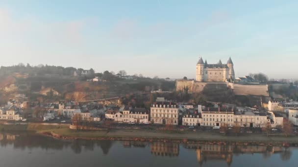 中世の城と教会が日の出 ロワール渓谷 フランスの川に反映しているSaumur町のスカイライン 空中ドローン撮影 右パンニングと町や川を明らかに — ストック動画