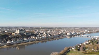 Saumur kasabası, ortaçağ şatosu ve kilisesiyle gündoğumunda nehre yansıyan, Loire Vadisi, Fransa. Hava aracı görüntüsü, yükselen kaide, manzarayı ortaya çıkarıyor.
