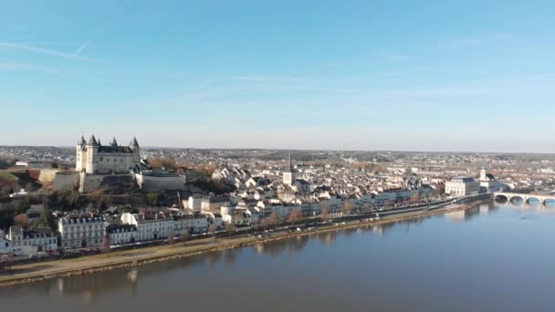 中世の城と教会が日の出 ロワール渓谷 フランスの川に反映しているSaumur町のスカイライン 空中ドローンドーリーショットとパンニング 町や川の橋を明らかに — ストック動画
