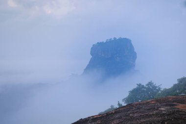 Çorak kaya ve su birikintisi. Gündoğumu gökyüzünün panorama görüntüsü ve su birikintisindeki yansıması, Pidurangala kayasının avantajlı noktasından, Sri Lanka 'daki ünlü Sigiriya Aslan Kayası' nın yanında..