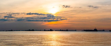 Kargo gemileri, petrol tankerleri ve gemi gemileri Singapur Dümeni boyunca demir attı, Singapur 'da, gün batımında.