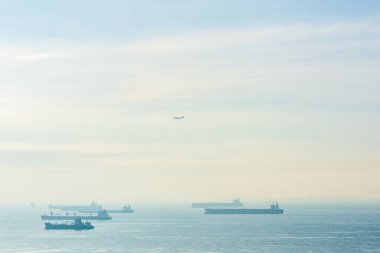 Kargo gemileri, petrol tankerleri ve gemi gemileri Singapur Dümeni boyunca demir attı, Singapur 'da, gün batımında.
