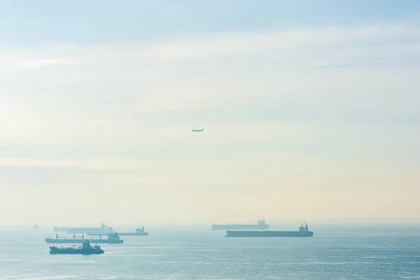 Kargo gemileri, petrol tankerleri ve gemi gemileri Singapur Dümeni boyunca demir attı, Singapur 'da, gün batımında.