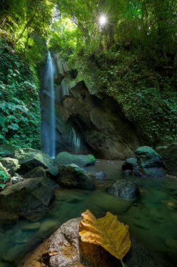 Pengempu waterfall and natural pool, with yellow palm leaf in central Bali Island, Indonesia clipart