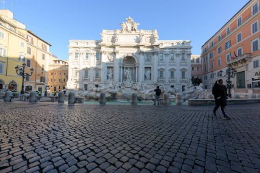 Roma, İtalya - 10 Mart 2020: Bir kadın terkedilmiş Trevi Fountain meydanından ayrılırken, yalnız bir adam Roma, İtalya 'da fotoğraf çekiyor. Bugün itibarıyla, İtalyan hükümeti ülke çapında bir karantina ilan etti. Seyahat ve toplanma yasakları sınırlıydı.