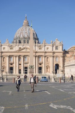 Roma, İtalya - 12 Mart 2020: Yüz maskesi takan turistler Vatikan, Vatikan 'daki boş bir Aziz Peter Meydanı' nda dolaşıyorlar. Koronavirüs salgınının ardından İtalya şu anda tecrit altında ve turistik alanlar terk edilmiş durumda..