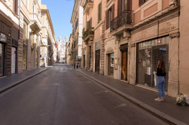 Roma, İtalya - 12 Mart 2020: Via dei Condotti 'de İspanyol Merdivenlerinin yanındaki kapalı dükkanların önünde bir kadın duruyor. Hükümetin hareket yasağı koyduğu bir kararın ardından, dışarıda kendi sertifikalarıyla bulunmalarını haklı çıkarmak gerekir. 