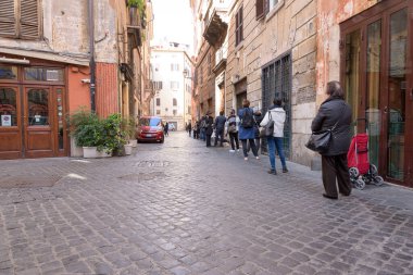 Roma, İtalya - 12 Mart 2020: Müşteriler İtalya 'nın orta kesimindeki yerel bir süpermarketin önünde kuyruğa girdiler. Bir seferde sadece birkaç kişi girebilir ve hükümet kararıyla 1 metre mesafeyi koruyacaktır. Bugün, İtalyan hükümeti bir ulusu