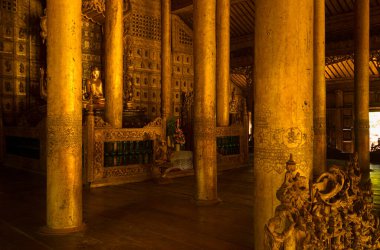 Mandalay, Myanmar - 4 Haziran 2014: Buda 'nın yaldızlı bir resmi ana sunağın üzerinde, Schwenandaw Manastırı, Mandalay, Myanmar' da boyanmış odun sütunlarının arasında duruyor.