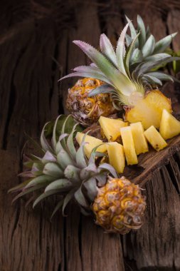 Ananas dilimleri ve eski ahşap arka plan üzerinde kabuklu ananas