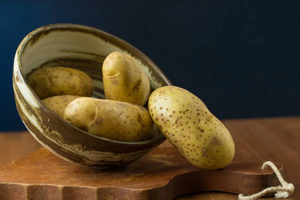 Pile of potatoes in bowl on wooden table