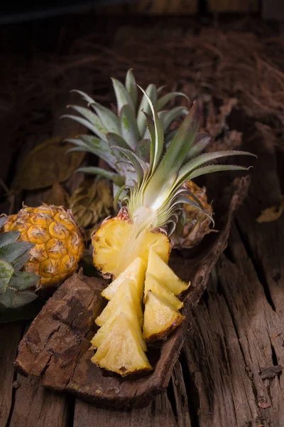 Ananas dilimleri ve eski ahşap arka plan üzerinde kabuklu ananas
