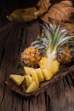 Ananas dilimleri ve eski ahşap arka plan üzerinde kabuklu ananas