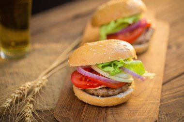 Peynirli hamburger ızgara et, peynir, domates, Kraft kağıt ahşap yüzeyi tarih ile. Fast food şablonu