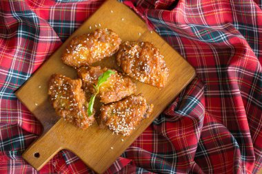 Ahşap tahta üzerinde kırmızı baharatlı soslu ızgara tavuk kanadı