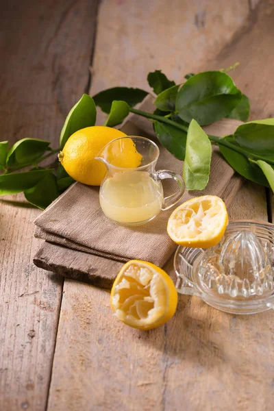 絞りたてのレモン汁 レモン絞り器や木製の背景に熟したレモンのガラスのボウル — ストック写真