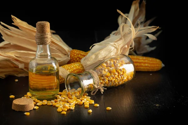 黑色背景下的玉米油和玉米籽粒 — 图库照片