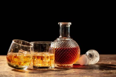 Şişe viski ve viski siyah arka plan üzerine buzlu cam