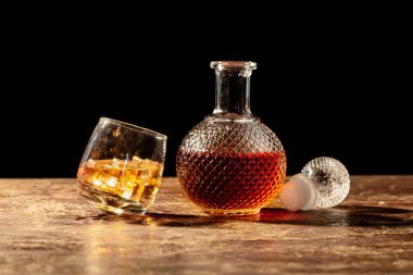 Şişe viski ve viski siyah arka plan üzerine buzlu cam