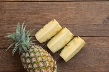 Ananas dilimleri ve eski ahşap arka plan üzerinde kabuklu ananas