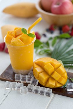 Olgun Mango Smoothies buz küpleri ve meyve ahşap plaka üzerinde