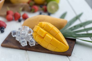 Ahşap plaka buz küpleri ve arka plan üzerinde meyve olgun Mango