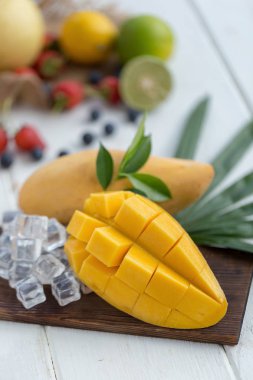 Ahşap plaka buz küpleri ve arka plan üzerinde meyve olgun Mango