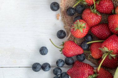 Beyaz ahşap zemin üzerinde bir yaban mersini ve çilek.