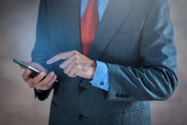 Smartphone gri arka plan üzerinde çalıştığı iş adamı