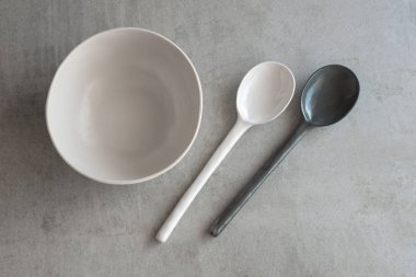 Beyaz kase ve gri arka plan üzerinde seramik kaşık