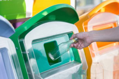 Eli boş cam şişe çöp kutusuna atma